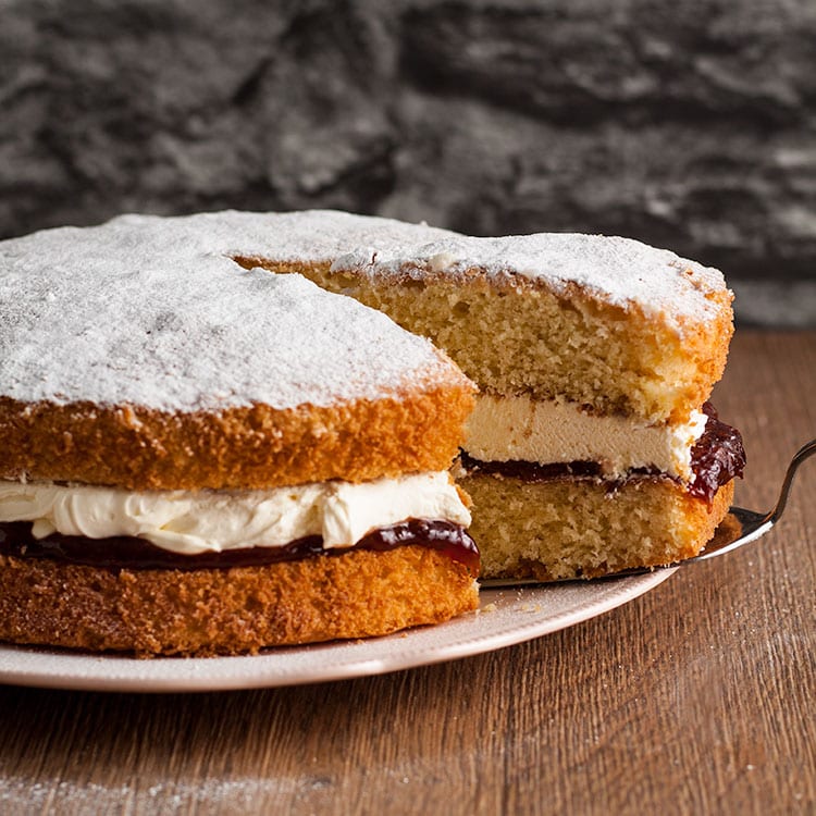 Victoria sandwich with slice partly removed on a cake slice.