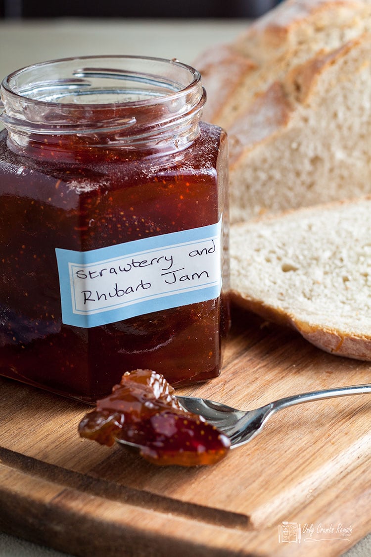 ar of strawberry and rhubarb jam with a spoonful of jam in front.