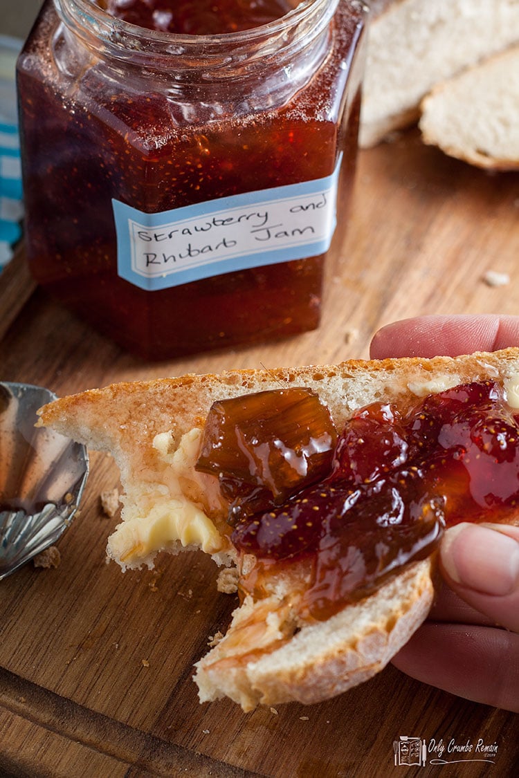 strawberry and rhubarb jam spread on bread with a bite taken out.